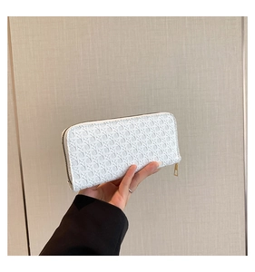Detail of white woven long clutch wallet featuring diamond pattern and gold zipper hardware