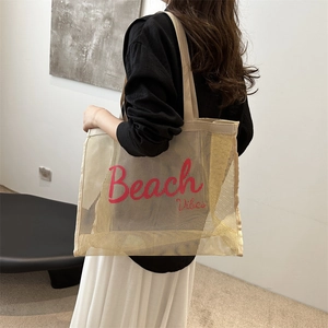 Mesh beach tote bag with red Beach Vibes text carried by model in minimal space