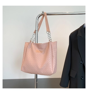 Detail of pink woven tote bag featuring a Fashion leather label and chain shoulder strap