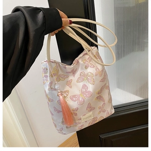 Détail de la broderie papillon sur un sac seau avec glands roses et étiquette mode