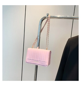 Detail of light pink quilted handbag featuring gold chain strap and fashion logo