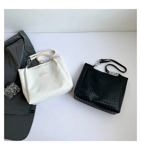 Close-up of woven tote bag texture with metal chain strap and fashion logo label