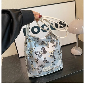 Détail du sac seau gris avec broderie papillon et décoration à pompon élégante