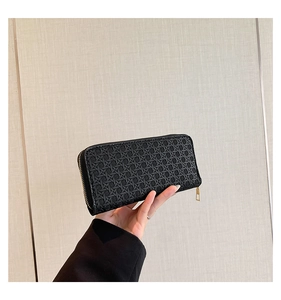 Close-up of black woven texture long wallet with gold zipper held in hand