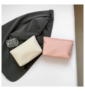 Detailed top view of beige and pink woven envelope clutch bags with metal zipper closure
