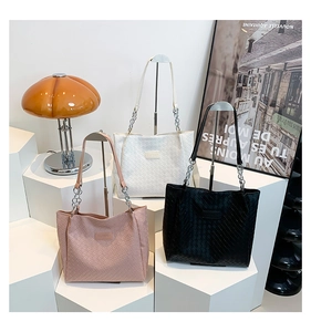 Detailed close-up of woven tote bags in white, black and pink with metal chain straps