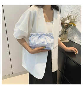 Detail of blue floral print on white ruched cloud clutch bag with metal clasp