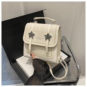 Detail of a cream mini backpack featuring star metal accents and elegant gold bead trim