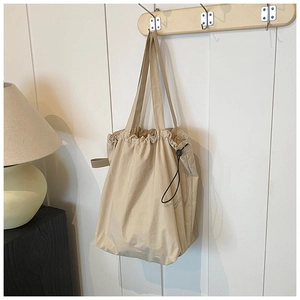 Detail of beige canvas drawstring tote bag with black adjustable buckle on a wall hook