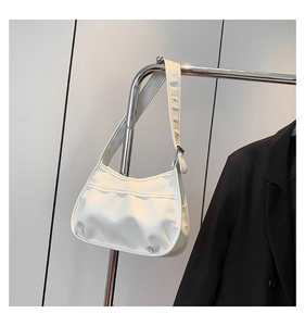 Detail of white pleated crescent bag showing glossy texture and silver metal buckle