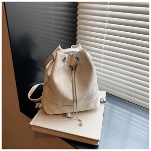 Close-up of cream bucket bag showing drawstring with pearl and butterfly metal details
