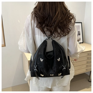 Vue détaillée du sac cabas noir avec papillons argentés et texture vintage sur modèle