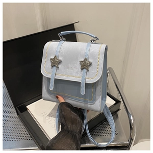 Detail view of light blue leather bag with metal stars and yellow stitching accents