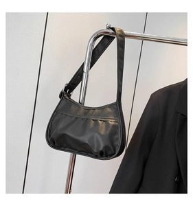 Detail of black pleated nylon hobo bag featuring a crescent shape and smooth texture