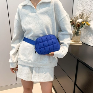 Sac banane matelassé bleu avec bandoulière réglable porté par un mannequin
