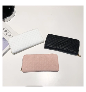 Three large woven long wallets in black, white, and pink with gold metal zippers