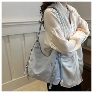 Détail du sac cabas bleu clair avec papillons dorés et bandoulière ajustable sur un modèle