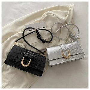 Détail de sacs en cuir embossé crocodile noir et argent avec boucles dorées en forme de U