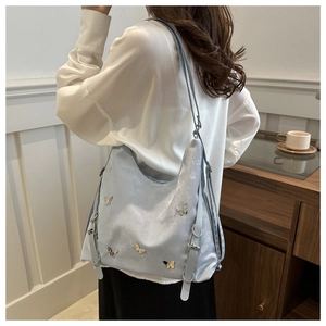 Détail du sac Hobo bleu clair avec papillon en métal et boucle argentée sur la bandoulière