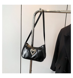 Detail of black patent leather crescent shoulder bag with a silver rhinestone heart charm