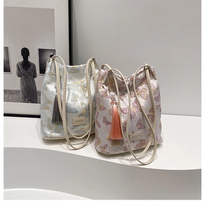 Détail de sacs seaux brodés de papillons avec texture velours et pompons