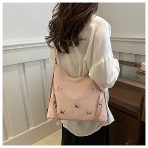 Détail latéral du sac Hobo rose avec papillons argentés sur la bandoulière réglable