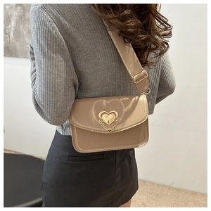 Khaki cross-body bag with heart metal buckle and wide fabric strap shown on model