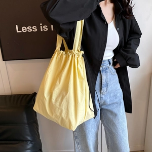 Minimalist yellow nylon drawstring tote bag shown in a high-quality lifestyle setting