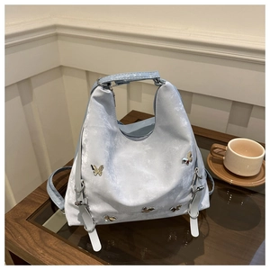 Détail du sac cabas bleu clair avec des papillons métalliques et une surface texturée