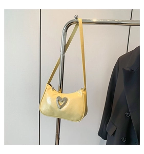 Detail of yellow baguette bag with silver heart rhinestone buckle and lychee leather texture