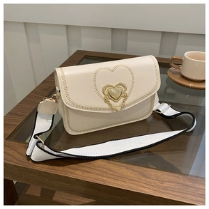 Detail of cream small square bag with golden heart lock and chic wide fabric strap
