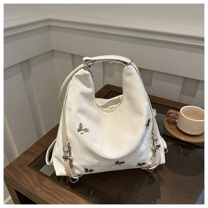 Détail du sac hobo blanc avec ornements papillons argentés et texture velours douce