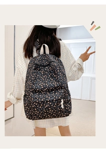 Detail of black floral backpack with tulip patterns and convenient front pocket storage