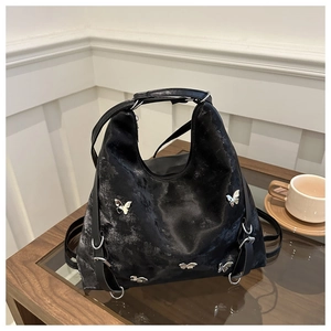 Détail du sac multifonctionnel noir avec breloques papillon en métal et sangles réglables