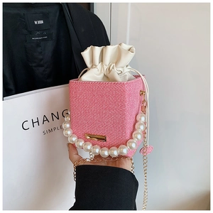 Detail of pink woven box bag featuring pearl handle and white drawstring inner lining