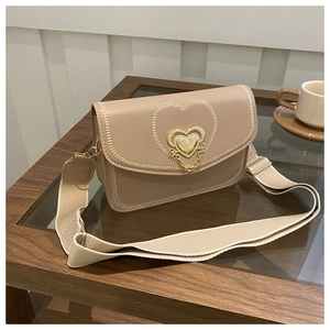 Detail of beige crossbody bag featuring heart-shaped embroidery and metal buckle clasp