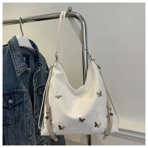 Gros plan du sac hobo blanc texturé avec un ornement de papillon en métal élégant