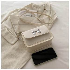 Détail du sac bandoulière blanc crème avec boucle papillon argentée sur cuir PU lisse