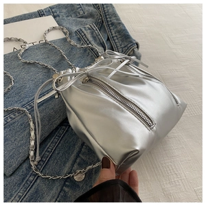 Détail d'un sac seau argenté métallisé avec zips latéraux et bandoulière chaîne