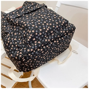 Detail of black floral nylon backpack with grey flower patterns and cream straps