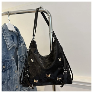 Détail du sac Hobo en cuir noir brillant avec des breloques papillons argentées