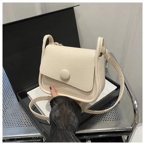 Detail der cremefarbenen Crossbody-Tasche mit Lychee-Leder, Rundschnalle und Gurt