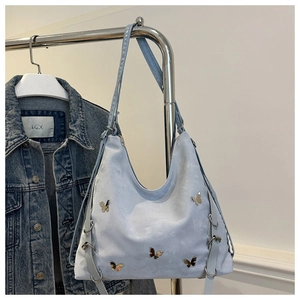 Gros plan sur le sac cabas en daim bleu clair orné de papillons en métal doré