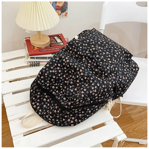 Close-up of black backpack with floral tulip pattern and beige canvas straps in a home setting