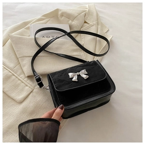 Détail du sac bandoulière noir avec nœud argenté et patchwork en velours et cuir