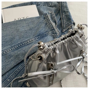 Détail du sac seau argenté métallisé avec bandoulière chaîne et fermoir sphérique design