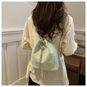 Détail du sac seau vert clair avec breloque papillon argentée et cordon en perles