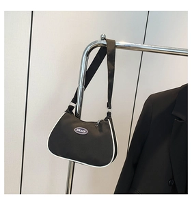 Detail of black nylon crescent bag featuring white piping and circular logo patch