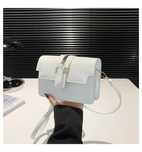 Close-up of elegant white glossy square handbag with gold hardware and fine stitching