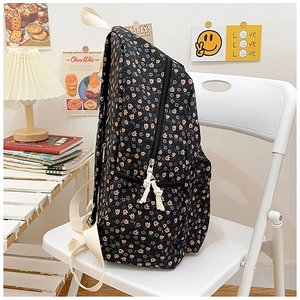Detail of floral canvas backpack with pink tulips on white chair in soft lighting
